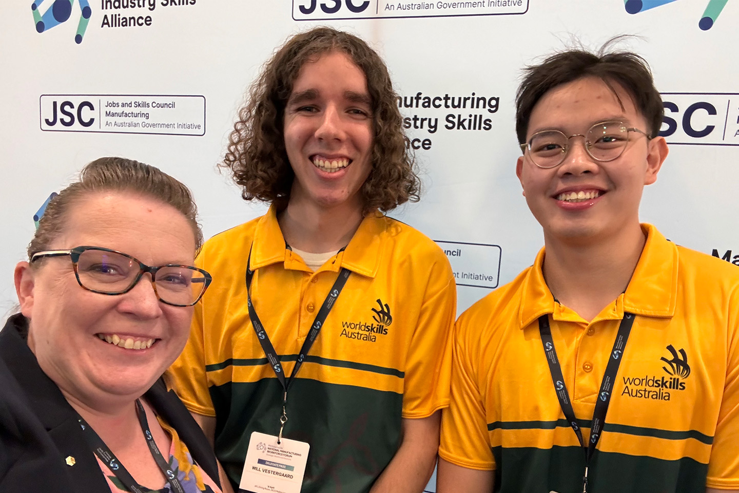 Jenny Mitchell taking a selfie with two student engineers in yellow shirts